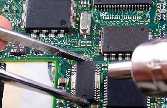 Close examination of microchip components during repair process in electronics workshop