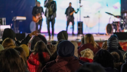 Live music performance engages audience on a vibrant night in the park, featuring local bands and illuminated stage backdrop