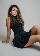 Portrait of a beautiful teenage girl in a black dress. Sitting pose.