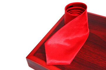 red tie rolled on wooden board closeup shot on white background 