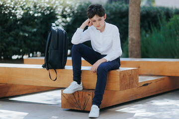Tired preteen student sitting alone during recess on a schoolyard bench