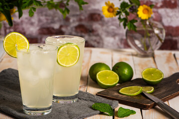 Glasses with ice and lime soda made from fruit juice, accompanied by lime slices. Close-up.