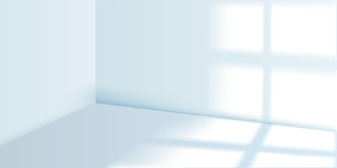 Fototapeta premium Empty room with soft light and shadow from windows on the walls and light blue floor. Interior of a minimalist studio. Soft abstract background for product presentation.