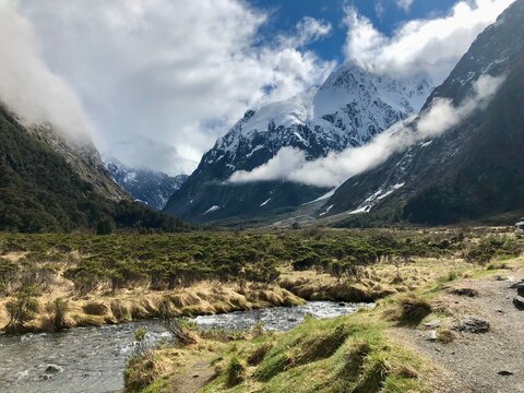 Rugged alpine valley framed by snow-capped mountains and dramatic clouds.