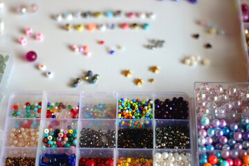 Friendship bracelet spelled with letter beads. Colorful handmade bracelets and various jewelry making supplies. Selective focus, white background.