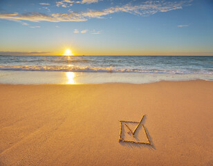 Check mark symbol in box on the beach shore during the sunset.