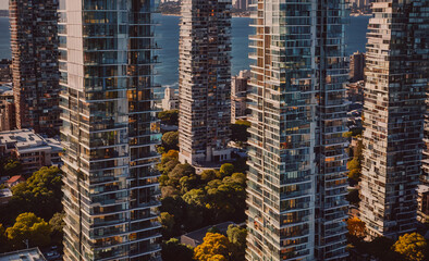 City skyline with tall buildings and a body of water in the background. The buildings are all made of glass and are very tall, creating a sense of grandeur and modernity. The water adds a sense of