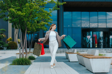 Elegant woman walks outdoors carrying large stylish shopping bags