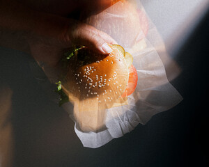 Artistic Motion Blur of Hand Holding Classic Burger in Dramatic Light