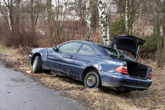 Wreck of Mercedes-Benz CLK Coupe W208 car with damaged fender, rear side view with open trunk