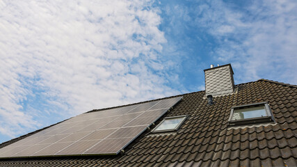 Photovoltaic panels providing green energy on rooftop under cloudy sky