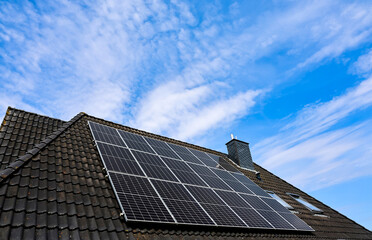 Fototapeta premium Photovoltaic panels providing clean energy on rooftop against blue sky