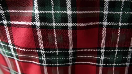 Close-up video of a red, green, and white tartan fabric texture with a visible weave pattern, ideal for backgrounds or design elements. - Powered by Adobe
