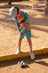 Man and boy playing petanque in hot country, father and son in hotel playing on sand