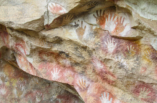 Cave of Hands in Argentina, cueva de las manos. Cave with hand arm prints on walls. Handprints made with red, yellow and black paint of ancient people on ceiling of a cave. Ancient rock carvings