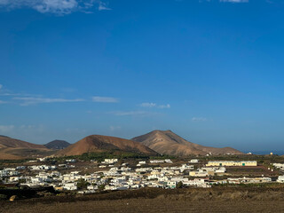 Classic landscape with white buildings in a dry volcanic environment on Lanzarote. Picturesque contrasts between whitewashed houses, bright blue skies and earth tones throughout the Canary Islands. © helivideo