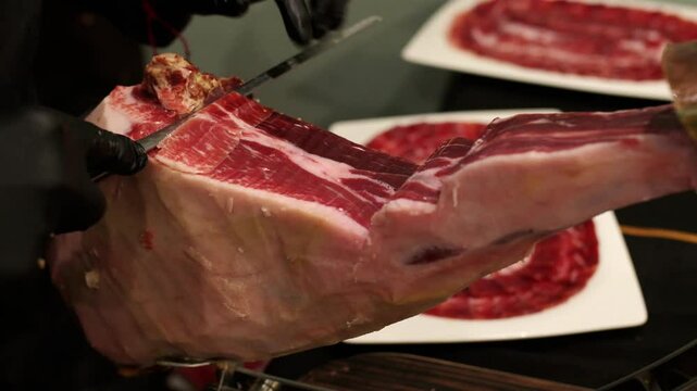Professional chef expertly slicing iberian acorn fed ham, showcasing the delicate marbling and texture of premium cured meat