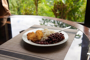 Rice and beans accompanied by a breaded tilapia fillet. Healthy Costa Rican lunch.