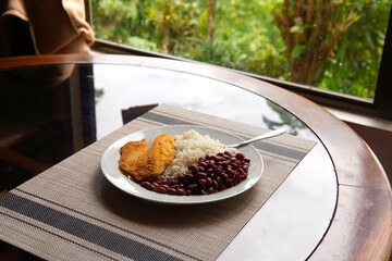 Rice and beans accompanied by a breaded tilapia fillet. Healthy Costa Rican lunch.