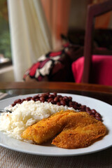 Rice and beans accompanied by a breaded tilapia fillet. Healthy Costa Rican lunch.