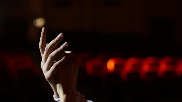Two hands gracefully move and expressively gesture against a dark theatrical background, bathed in dramatic spotlighting. Perfect for conveying emotion, storytelling, or artistic performance.