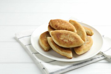 Delicious fried pyrizhky (stuffed pies) on white wooden table, closeup