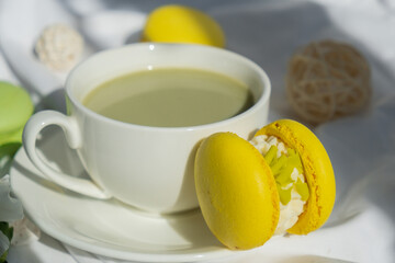 Sweet yellow macaron dessert Cup of green plant based matcha tea latte in cozy morning bed atmosphere. Creative holiday romantic date idea. Herbal prebiotic fiber superfood beverage antioxidant-rich