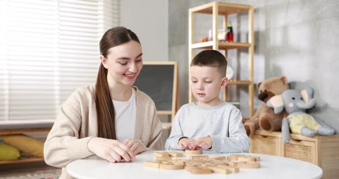 Dyslexia. Mother and her son learning letters at table indoors