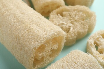 Natural loofah sponges on light blue background, closeup