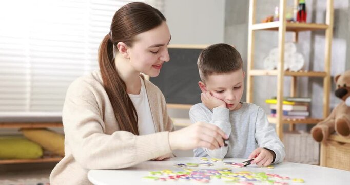 Dyslexia. Mother and her son learning letters at table indoors