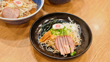 Delicious ramen dish featuring noodles, sliced meat, and fresh vegetables, served in black bowl.. Japanese food