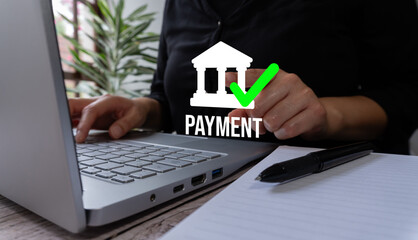 A person uses their laptop to make an online bank payment, with the word 