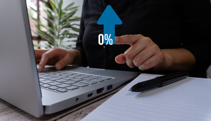 Person typing on a laptop pointing with his hand at a blue arrow pointing up and the text "0%" above it