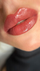 permanent makeup on the lips of a young woman of a delicate peach shade close-up, a girl after a...