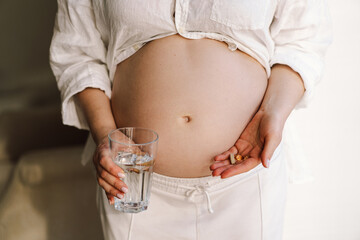 Pregnant young woman holding vitamins to maintain health of herself and her baby. Pregnancy and Health Concept