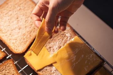 Hand placing a slice of cheese on bread