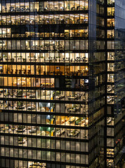 A high-rise office building at night with employees still at work.