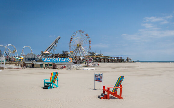 Wildwood beach giant adirondack chairs with ferris wheel and rides pre-season on a bright sunny day 