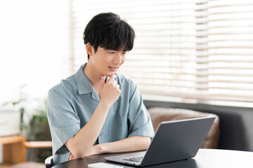 若い日本人男性がノートパソコンを開き、オンラインミーティングをしている。