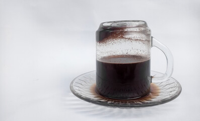 Traditional Indonesian-style black coffee served upside down in a clear glass, showcasing rustic beverage culture.