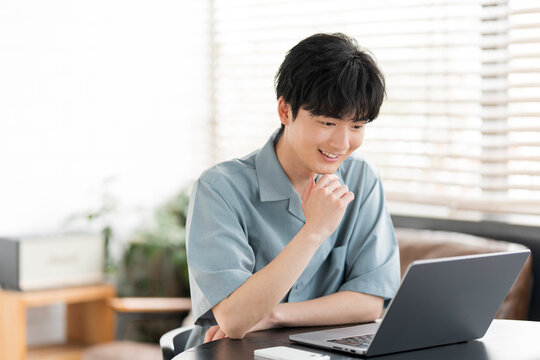 若い日本人男性がノートパソコンを開き作業をしている。