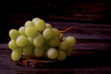 Freshly picked green grapes glisten with moisture on a rustic wooden surface