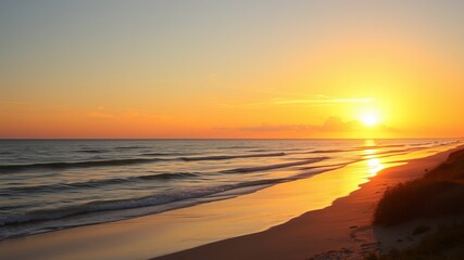 A breathtaking sunset paints the ocean and sandy beach with vibrant orange and golden hues creating a serene coastal landscape.