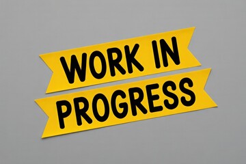 Yellow Ribbons with Work in Progress Text on Gray Background Indicating Project Development