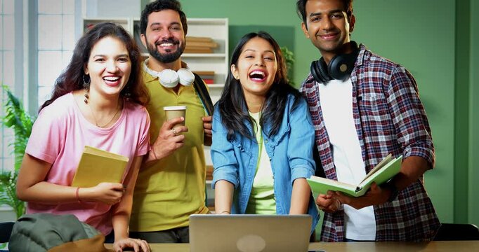 Indian college students using laptop for completing group assignment, standing with books and notes, working together in friendly college library environment, focused on academic teamwork - Powered by Adobe