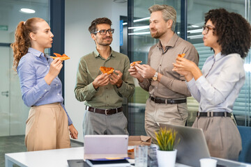 Happy multiracial colleagues have fun at lunch break in office. Excited workers celebrate shared win ordering takeaway pizza