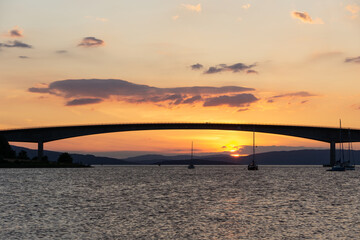 Sailboats sailing under Skye Bridge at sunset in Isle of Skye, Scottish Highlands