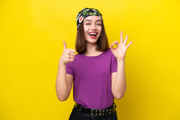 Young Ukrainian woman isolated on yellow background showing ok sign and thumb up gesture