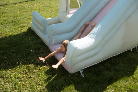 Girl lands face-first from inflatable slide onto grassy backyard