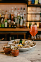 Oysters on cocktail shooters with lemon and sauce at a bar.
